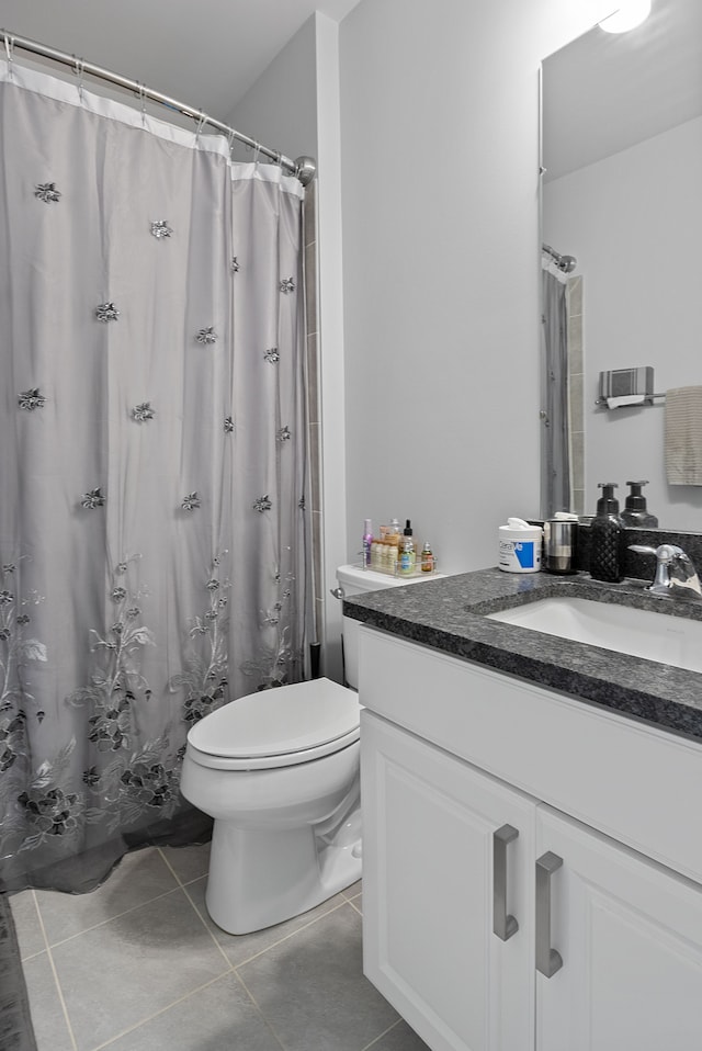 bathroom with tile patterned flooring, vanity, toilet, and walk in shower