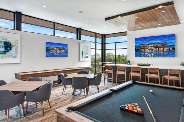 recreation room featuring expansive windows, hardwood / wood-style floors, indoor bar, and pool table