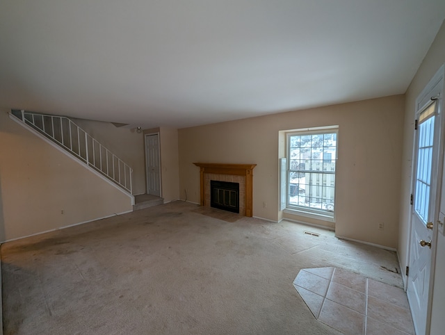 unfurnished living room featuring light carpet and a tile fireplace