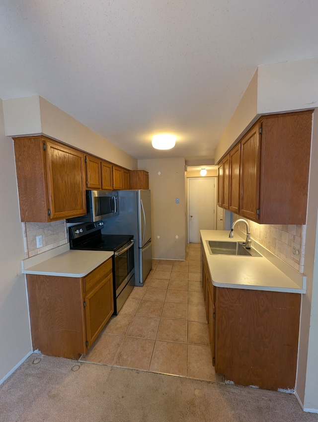 kitchen featuring appliances with stainless steel finishes, sink, light tile patterned floors, and backsplash