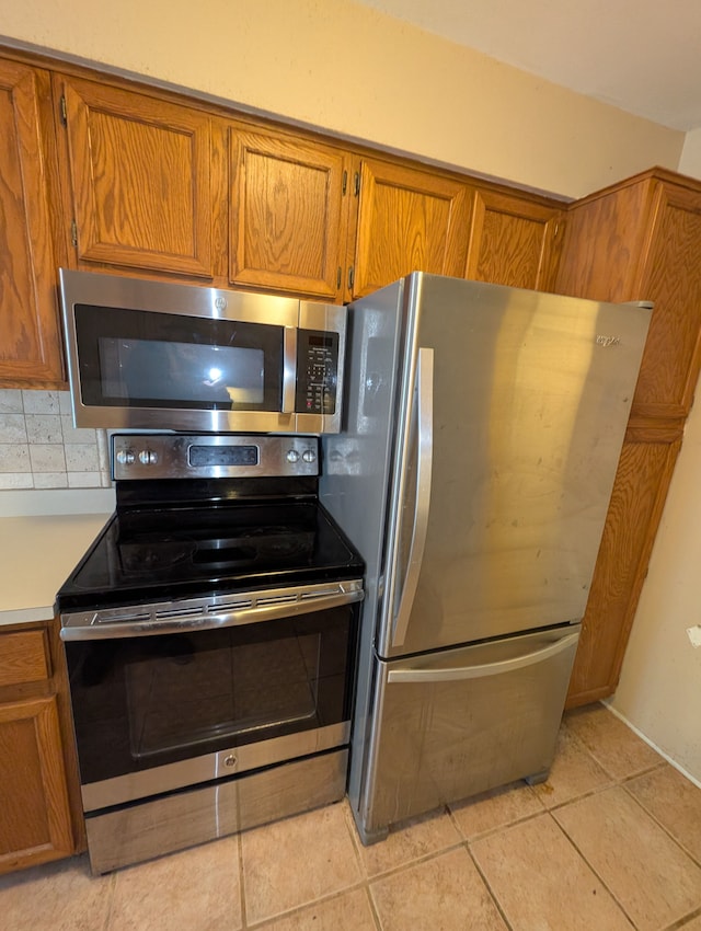 kitchen with tasteful backsplash, light tile patterned flooring, and appliances with stainless steel finishes