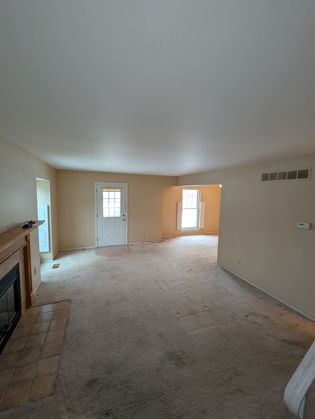 unfurnished living room with carpet flooring, a wealth of natural light, and a fireplace