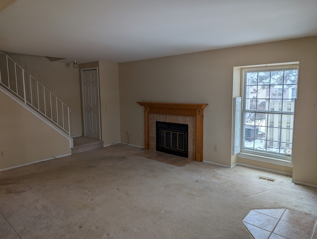 unfurnished living room featuring light colored carpet and a tile fireplace