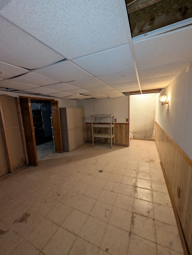 basement with a paneled ceiling and wooden walls