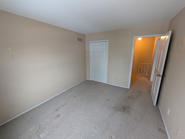 unfurnished bedroom with light colored carpet and a closet