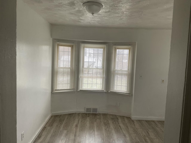 unfurnished room with a textured ceiling and light hardwood / wood-style flooring