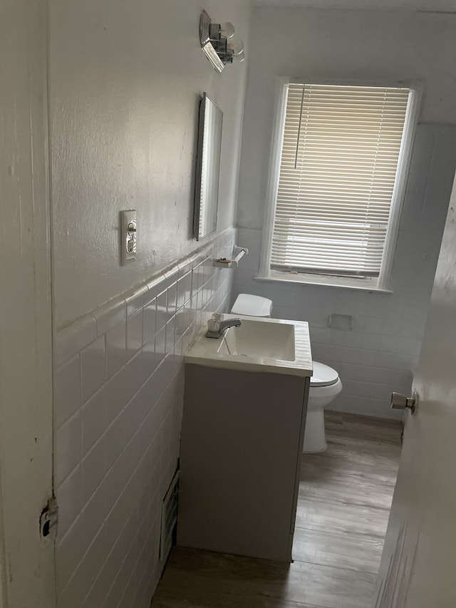 bathroom featuring hardwood / wood-style flooring, vanity, tile walls, and toilet