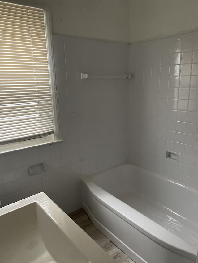 bathroom featuring a bath and tile walls