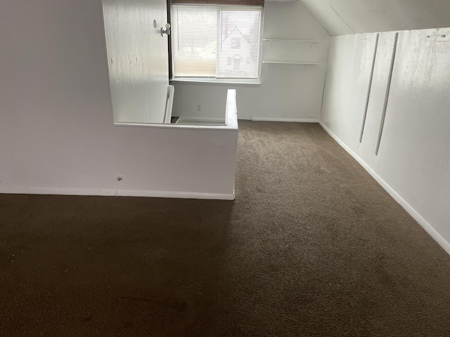 additional living space with dark carpet and lofted ceiling