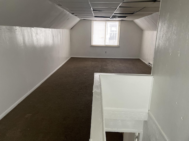 additional living space with vaulted ceiling and dark colored carpet