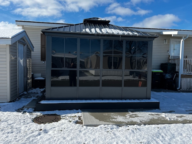 snow covered house featuring a sunroom