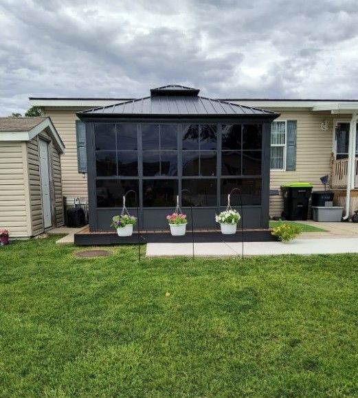 back of property with a shed, a lawn, and a sunroom