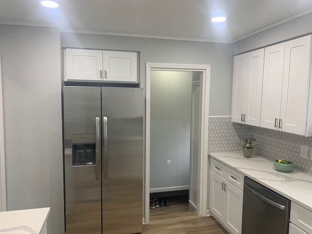 kitchen with light wood-type flooring, stainless steel appliances, white cabinetry, and light stone counters