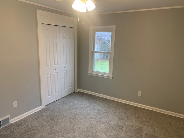 unfurnished bedroom featuring ceiling fan, a closet, carpet floors, and ornamental molding