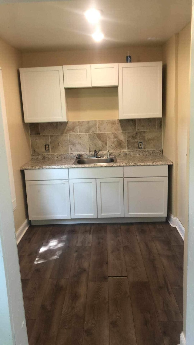 kitchen featuring sink, tasteful backsplash, dark hardwood / wood-style flooring, light stone counters, and white cabinetry