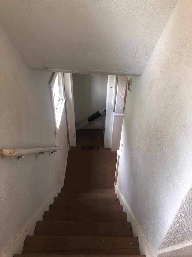 staircase featuring a textured ceiling