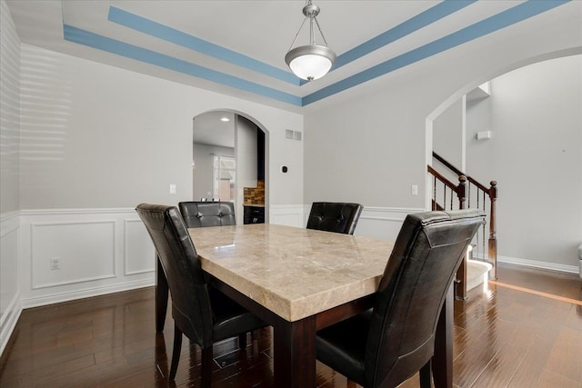 dining room with a raised ceiling and dark hardwood / wood-style flooring