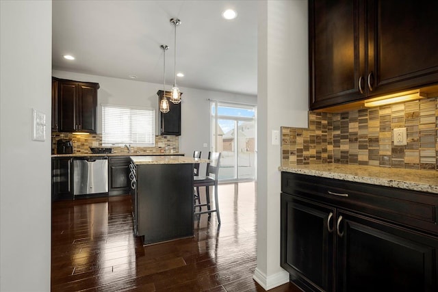 kitchen with tasteful backsplash, stainless steel dishwasher, pendant lighting, dark hardwood / wood-style floors, and a kitchen island