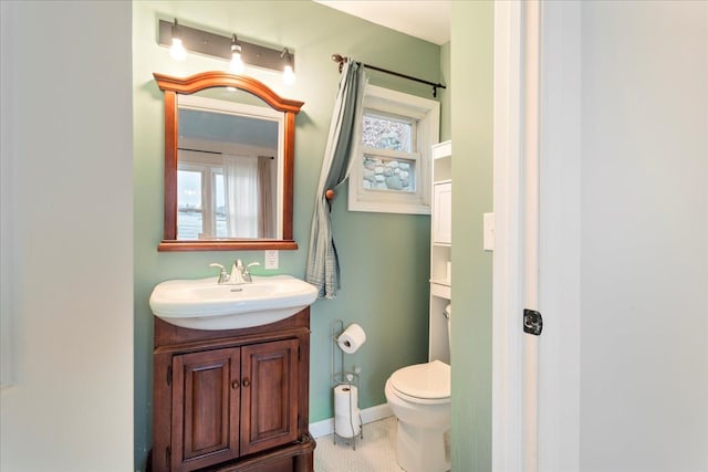 bathroom with toilet, baseboards, and vanity