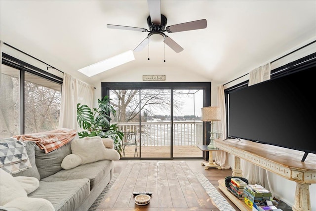 living room featuring ceiling fan, hardwood / wood-style floors, and lofted ceiling with skylight