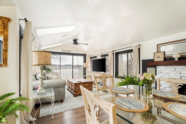 dining area with lofted ceiling with skylight, dark hardwood / wood-style flooring, and ceiling fan