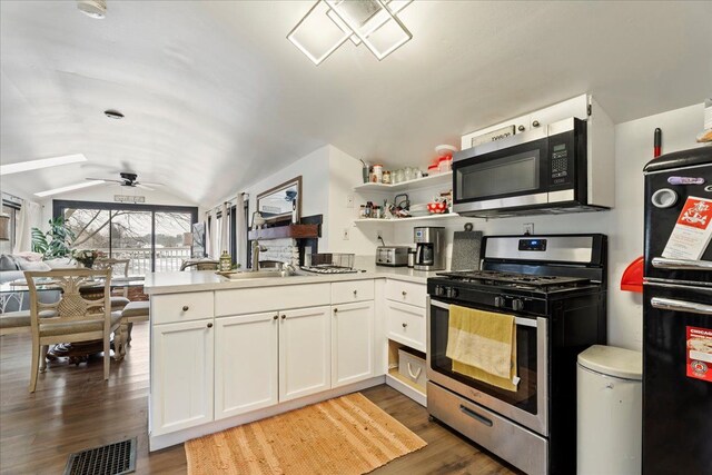 kitchen featuring appliances with stainless steel finishes, dark hardwood / wood-style flooring, lofted ceiling with skylight, ceiling fan, and white cabinets