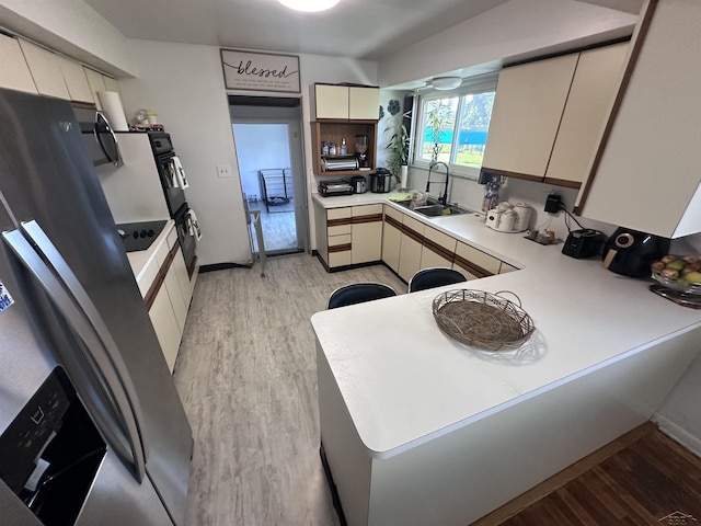 kitchen featuring appliances with stainless steel finishes, sink, light hardwood / wood-style flooring, and kitchen peninsula