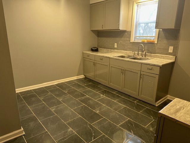 kitchen featuring gray cabinetry, decorative backsplash, and sink