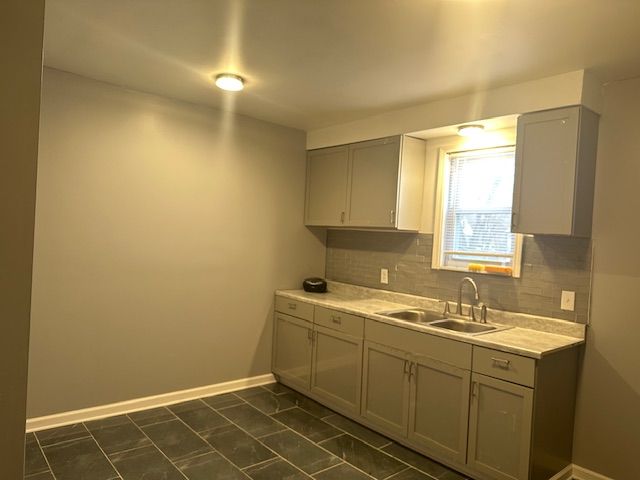 kitchen with gray cabinets, tasteful backsplash, and sink