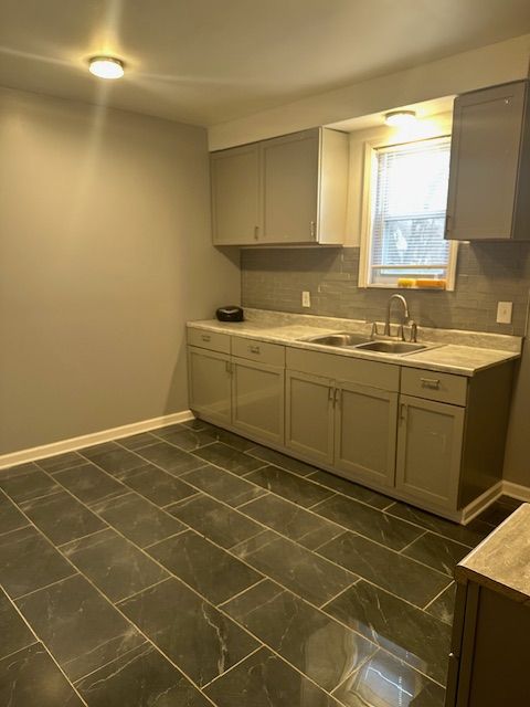 kitchen featuring tasteful backsplash, gray cabinets, and sink