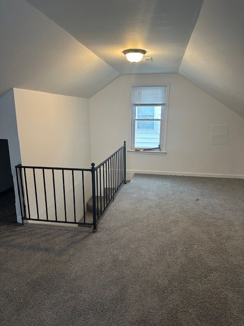 bonus room featuring lofted ceiling and dark colored carpet