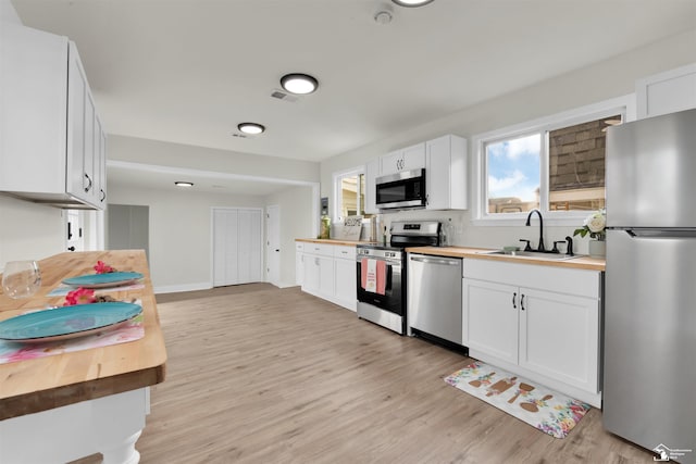 kitchen with white cabinets, butcher block counters, sink, and appliances with stainless steel finishes