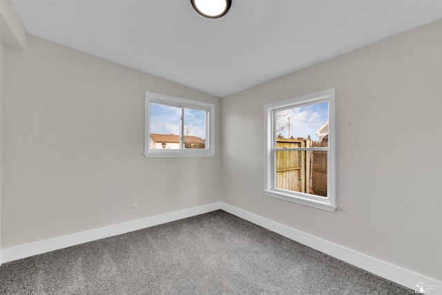 carpeted spare room featuring a healthy amount of sunlight and lofted ceiling