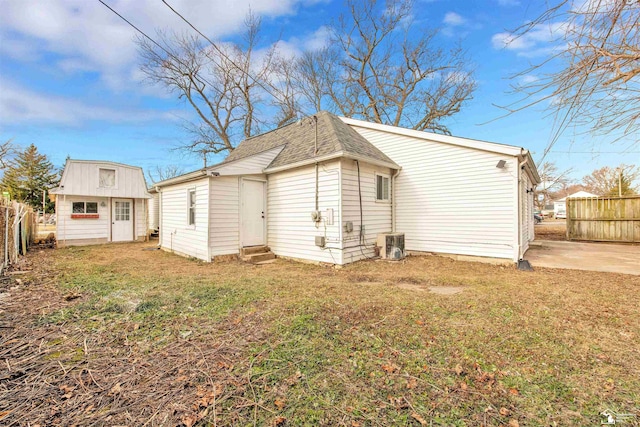 back of property featuring a lawn and central air condition unit