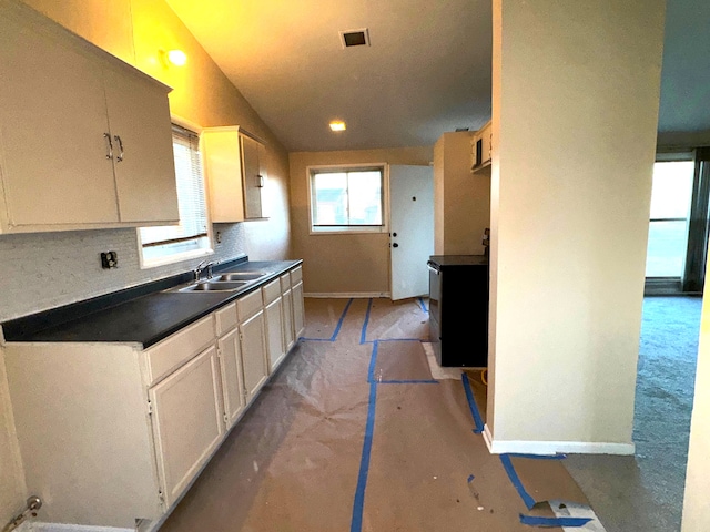 kitchen featuring backsplash, lofted ceiling, and sink