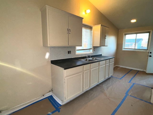 kitchen with backsplash, white cabinetry, vaulted ceiling, and sink