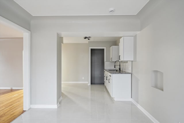 kitchen with dark stone countertops, white cabinetry, sink, and light tile patterned floors