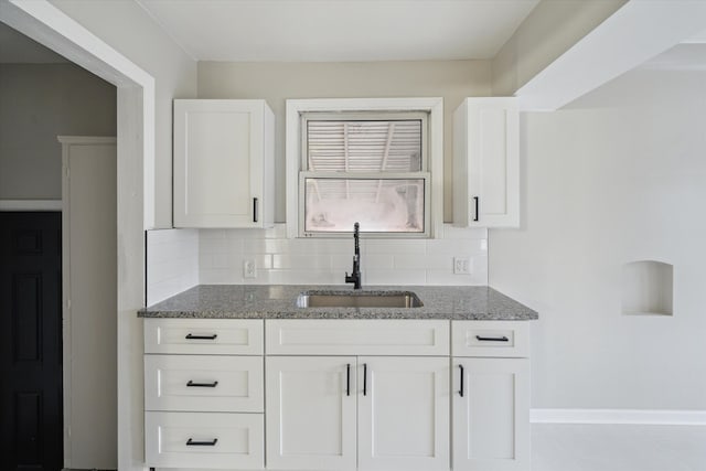 kitchen with decorative backsplash, white cabinets, and sink