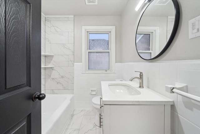 full bathroom with vanity, toilet, tile walls, and tiled shower / bath