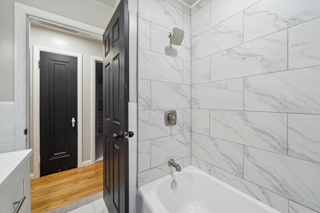 bathroom with tiled shower / bath combo, wood-type flooring, and vanity