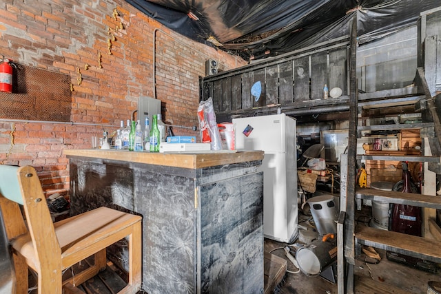 bar featuring brick wall and white refrigerator