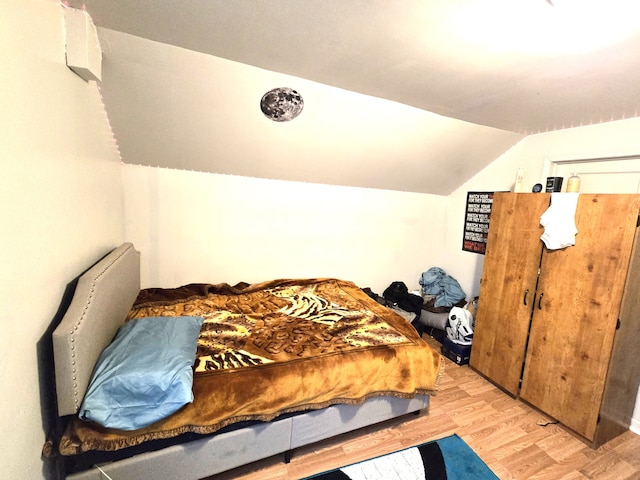 bedroom featuring light wood-type flooring and vaulted ceiling