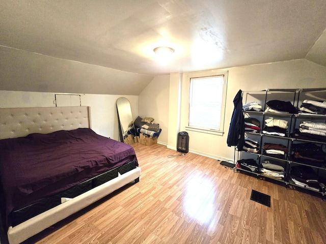 bedroom with hardwood / wood-style floors and lofted ceiling