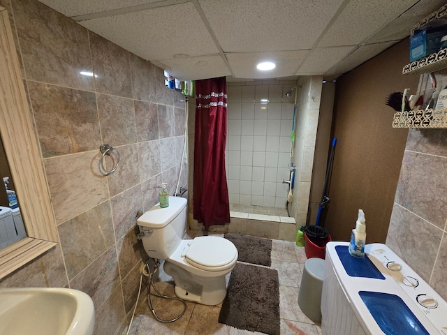 bathroom with a drop ceiling, walk in shower, tile patterned floors, toilet, and tile walls