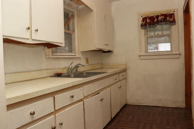 kitchen featuring dark parquet flooring, white cabinetry, and sink