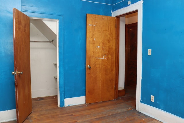 unfurnished bedroom featuring a closet and dark wood-type flooring