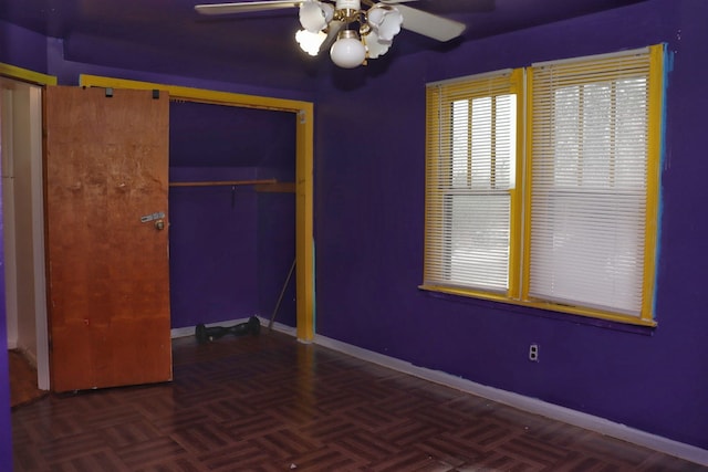 unfurnished bedroom with ceiling fan, a closet, and dark parquet floors