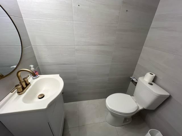 bathroom featuring tile walls, vanity, and toilet