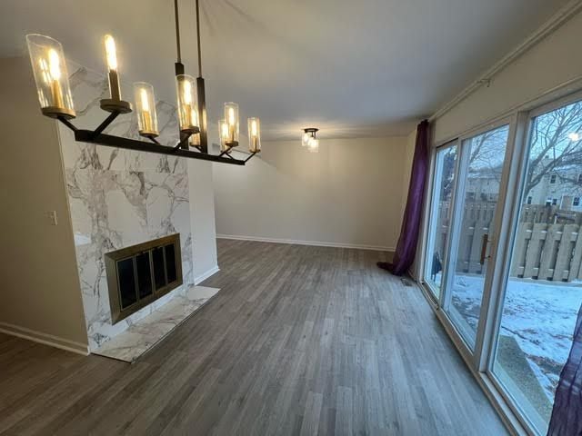 unfurnished living room with dark hardwood / wood-style flooring, ornamental molding, a notable chandelier, and a high end fireplace