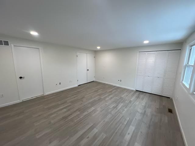 unfurnished bedroom with wood-type flooring and two closets